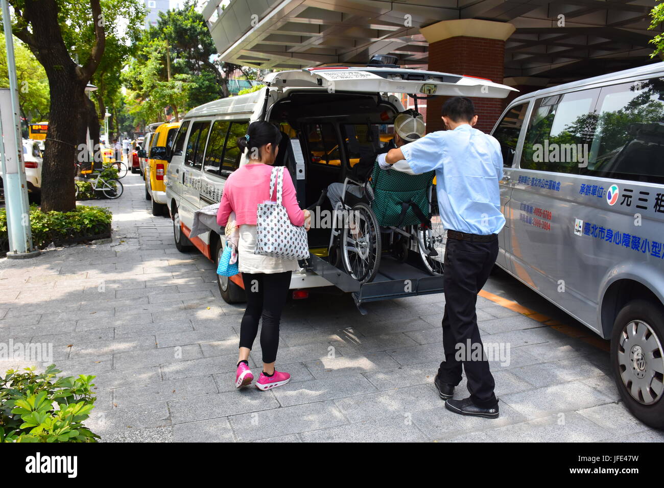 A person helping someone in a wheel chair to exit a van at the Mackay hospital in Taipei, Taiwan