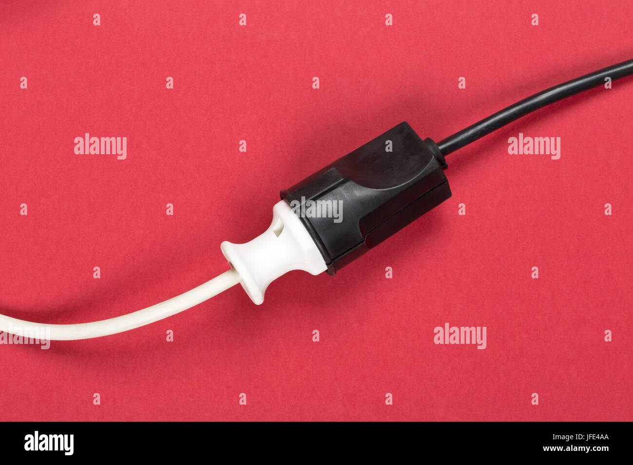 Connected white european power cable plug with black connector cable on red background Stock Photo