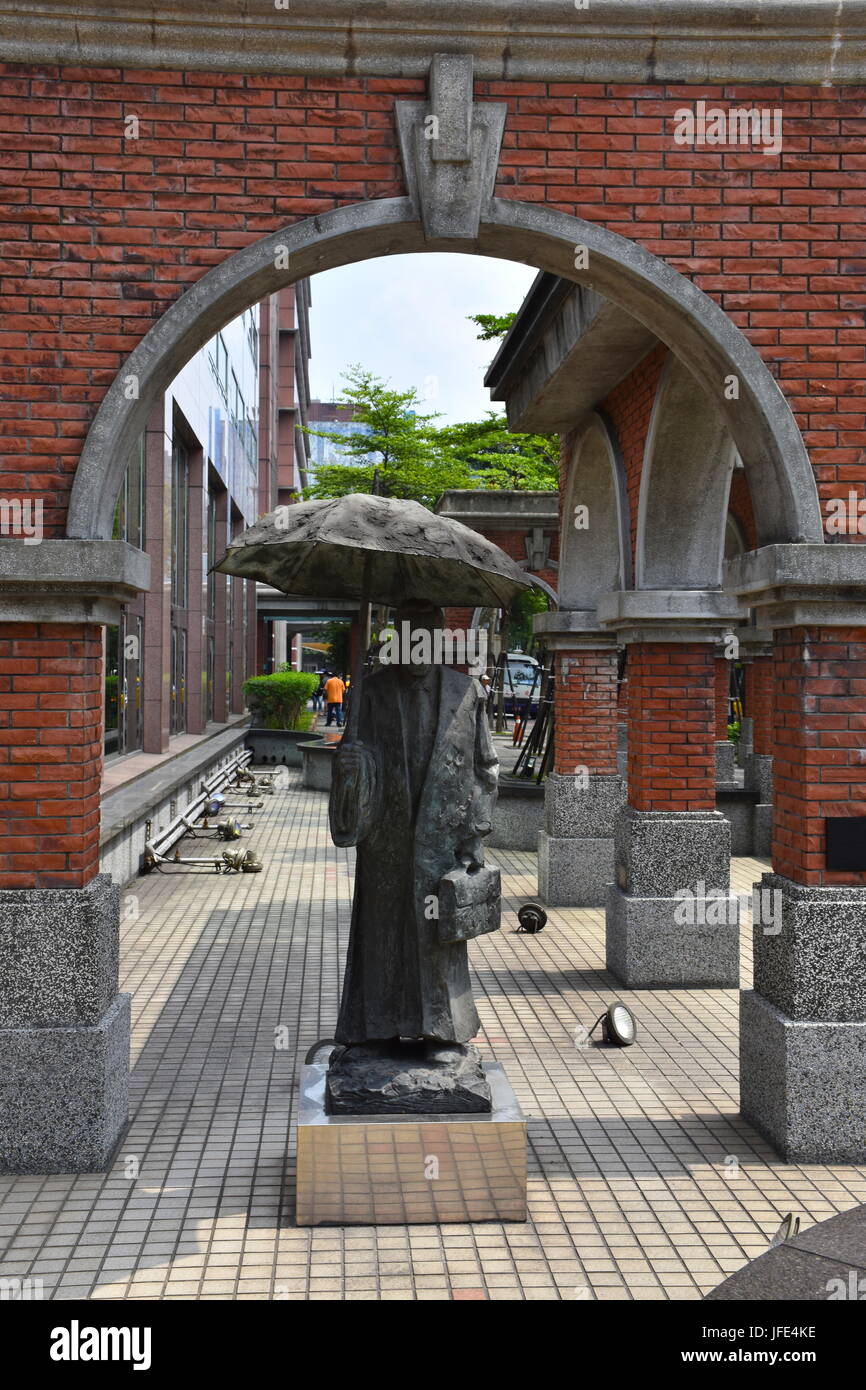 This old man statue with an umbrella is in front of Mackay Hospital, Taipei, Taiwan. A beautiful bronze sculpture. Stock Photo