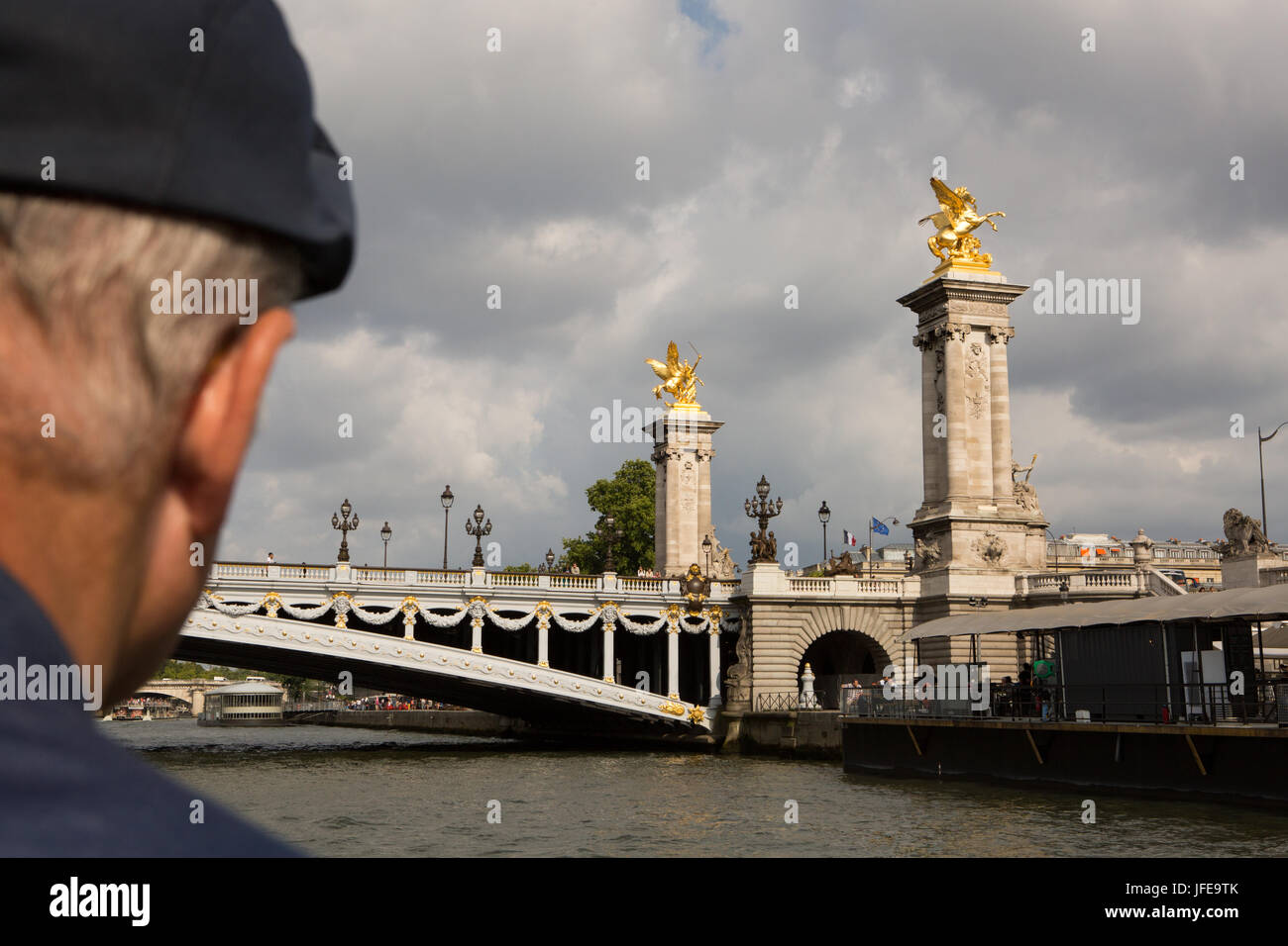 A man views the Pont de Alexandre III from a boat cruising on the Seine River. Stock Photo