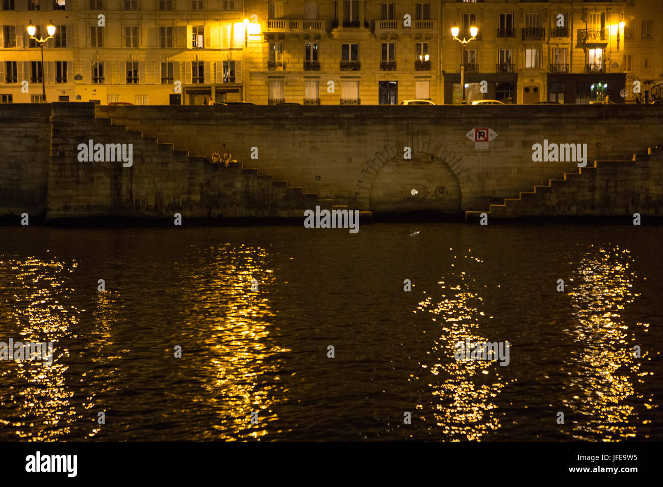 The city lights of Paris reflect in the waters of the Seine River. Stock Photo