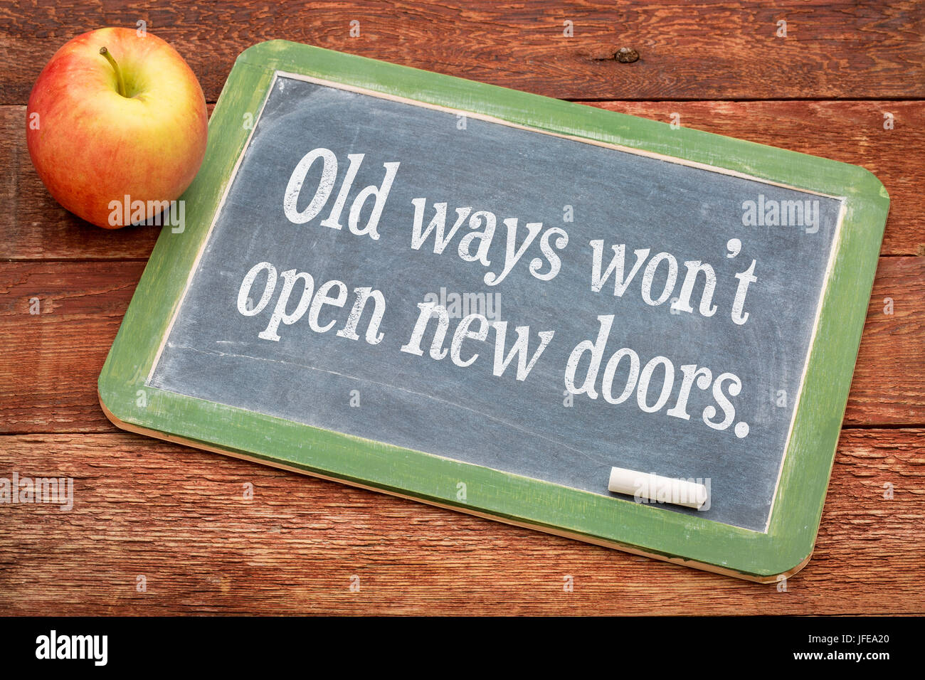 Old ways do not open new doors - motivational quote on a slate blackboard against red barn wood Stock Photo