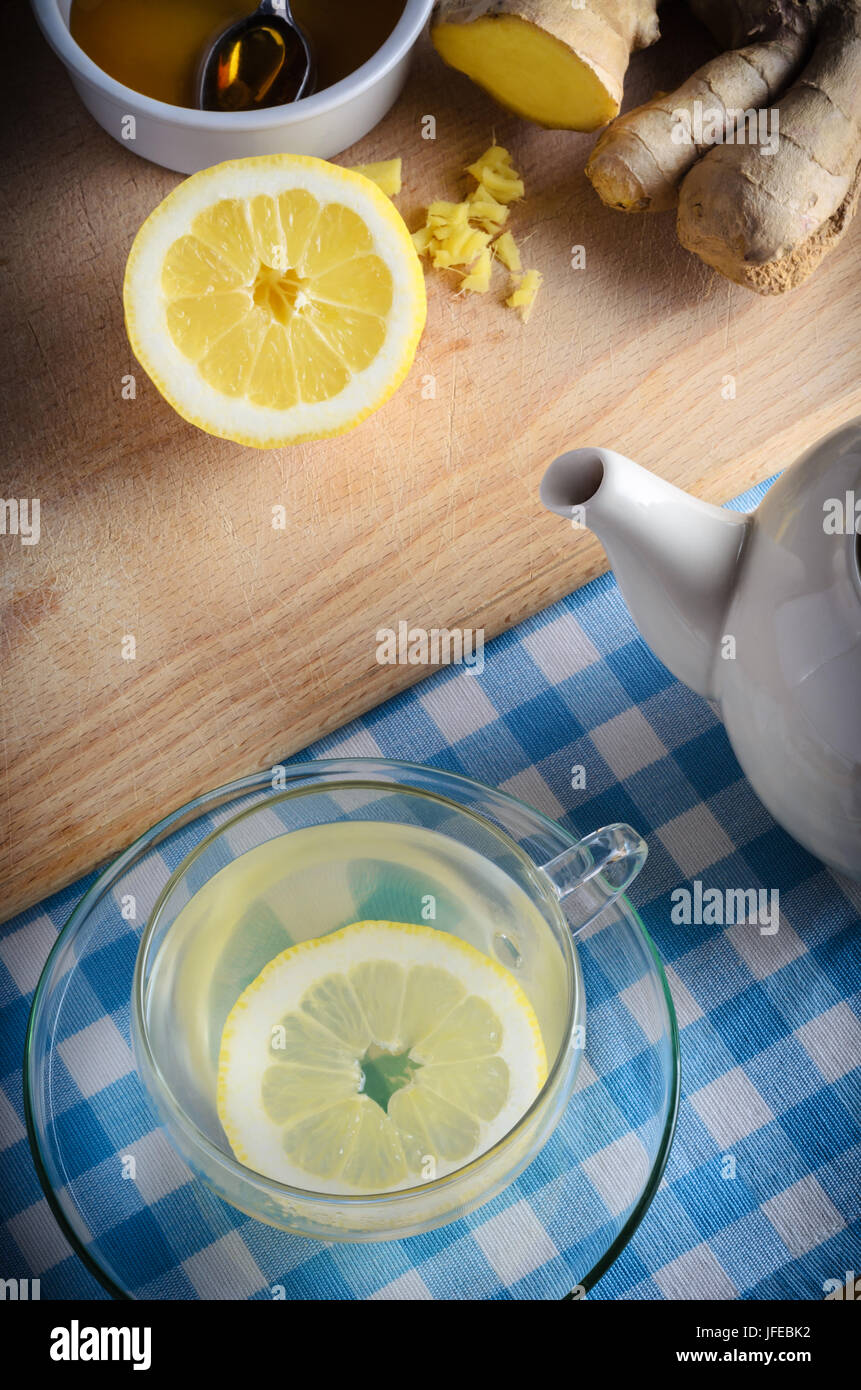 Vertical kitchen preparation scene containing ingredients for a honey, lemon and ginger drink - a herbal home remedy for the cold and flu season. Stock Photo