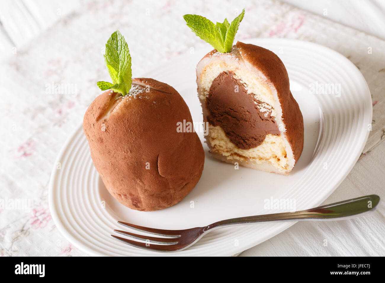 Sliced chocolate rum balls cake with mint and cocoa powder close-up on a plate on a table. horizontal Stock Photo