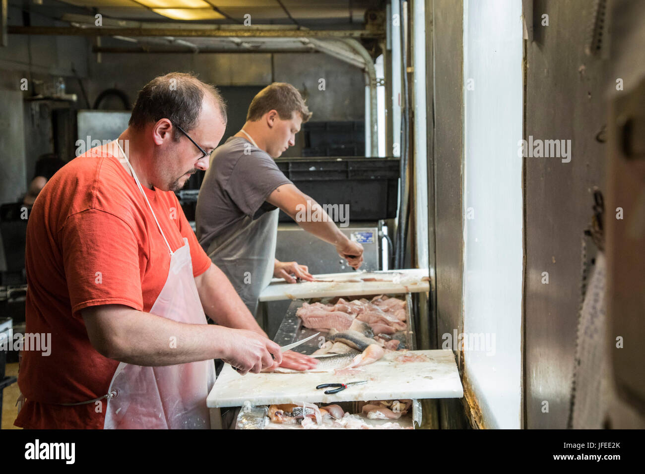 Charlevoix, Michigan - Workers clean and fillet whitefish at the John Cross Fish Market. The fish were caught in Lake Michigan. Stock Photo