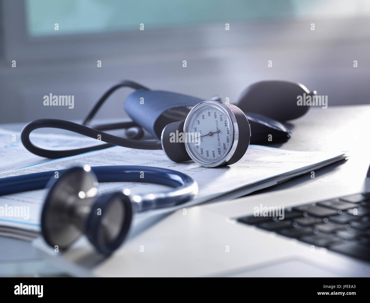 Blood pressure gauge and stethoscope sitting on a doctors desk. Stock Photo