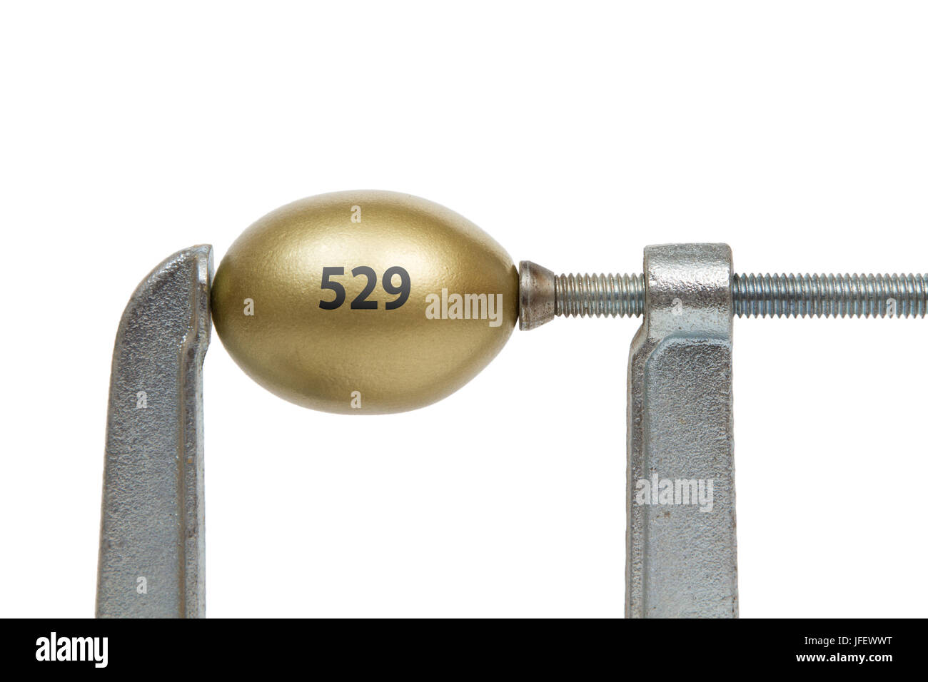 A golden nest egg with "529" text  squeezed between a metal clamp. Stock Photo