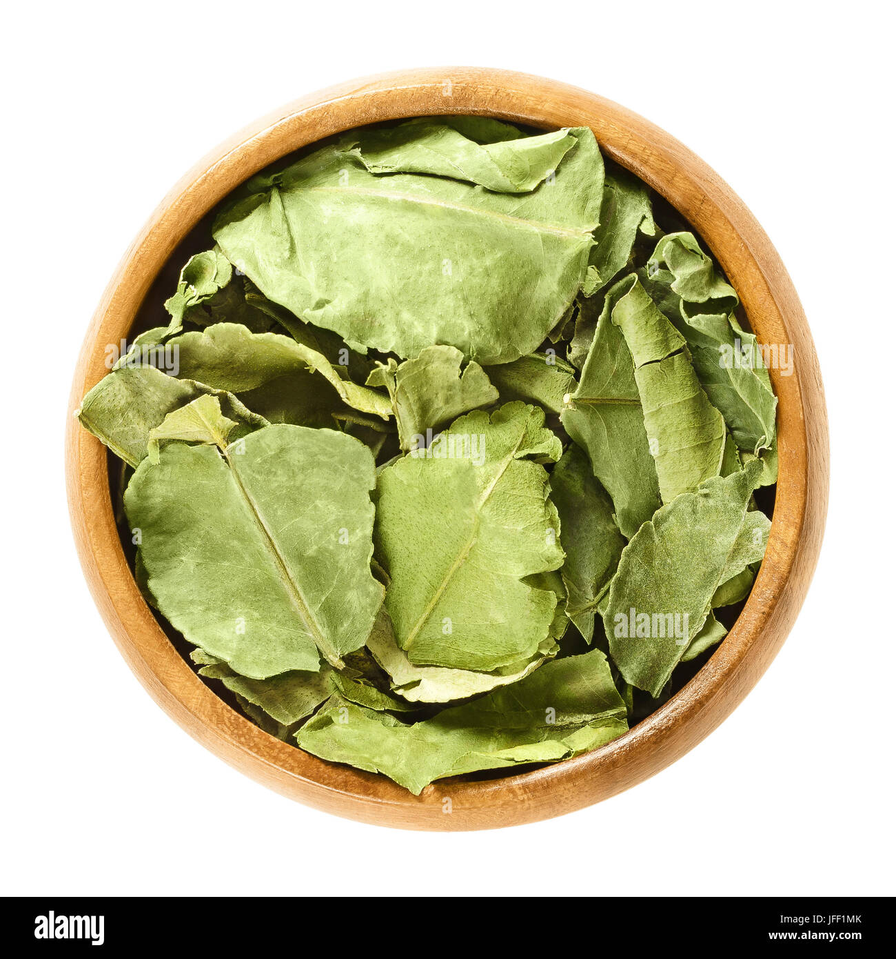 Dried kaffir lime leaves in wooden bowl. Green leaves of Citrus hystrix, also makrut lime or Mauritius papeda. Asian citrus fruit plant. Stock Photo