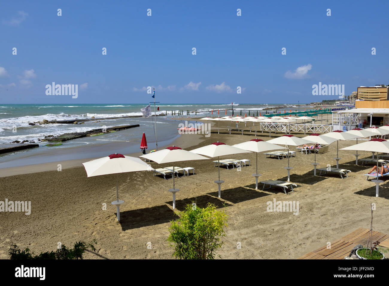 Nearly deserted beach with umbrellas out on a windy summer day in Anzio, Italy Stock Photo