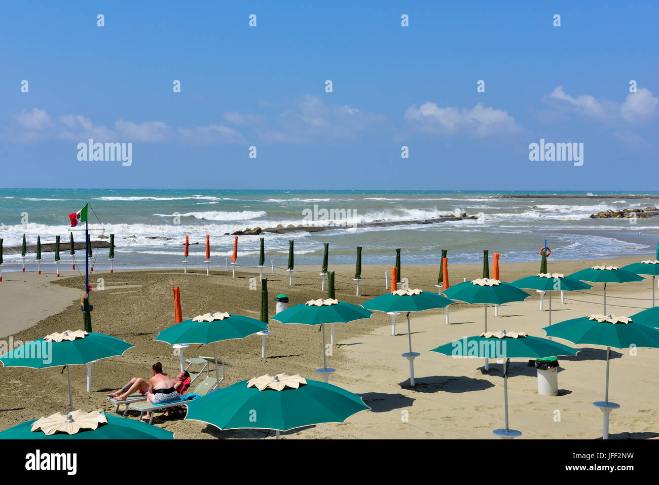 Nearly deserted beach with umbrellas out on a windy summer day in Anzio, Italy Stock Photo