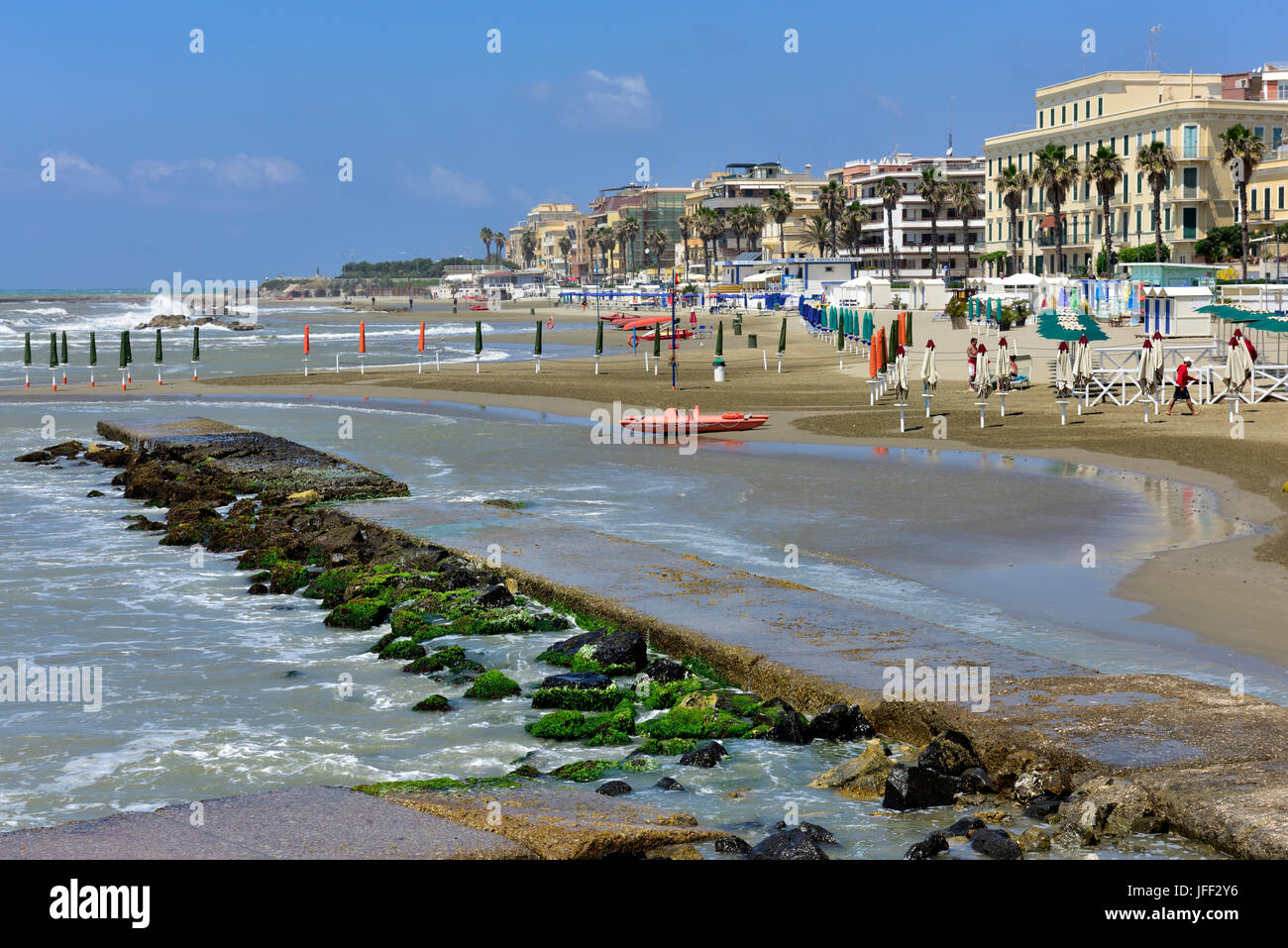 Nearly deserted beach with umbrellas and boats out on a windy summer day in Anzio, Italy Stock Photo