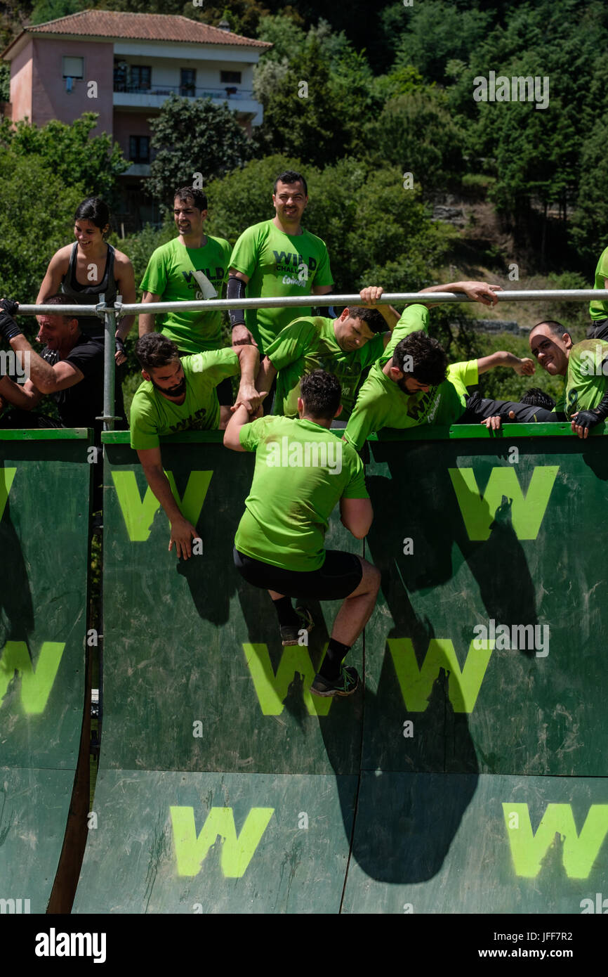 Competitors helping each other climb a wall during an obstacle course race Stock Photo