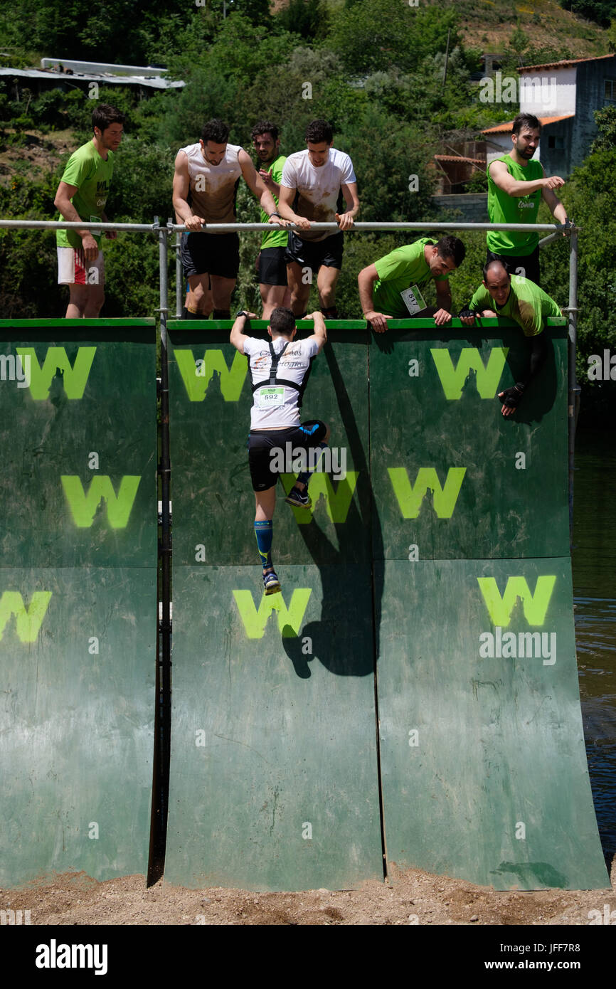 Competitors helping each other climb a wall during an obstacle course race Stock Photo