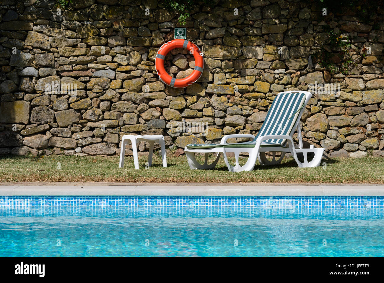 Sun lounger next to an outdoor swimming pool Stock Photo