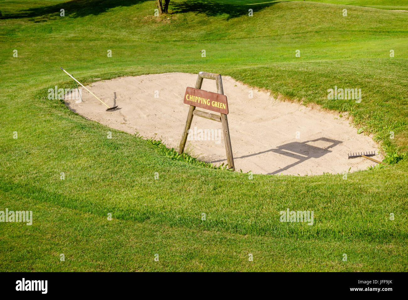 Chipping green sign in front of bunker on golf course, detail of golf