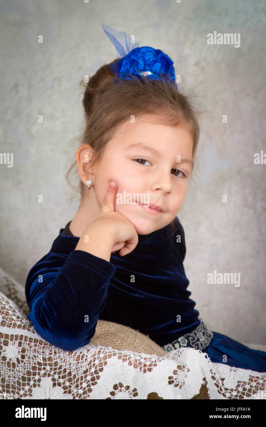 beautiful little girl princess in blue dress sitting on white chair and ...
