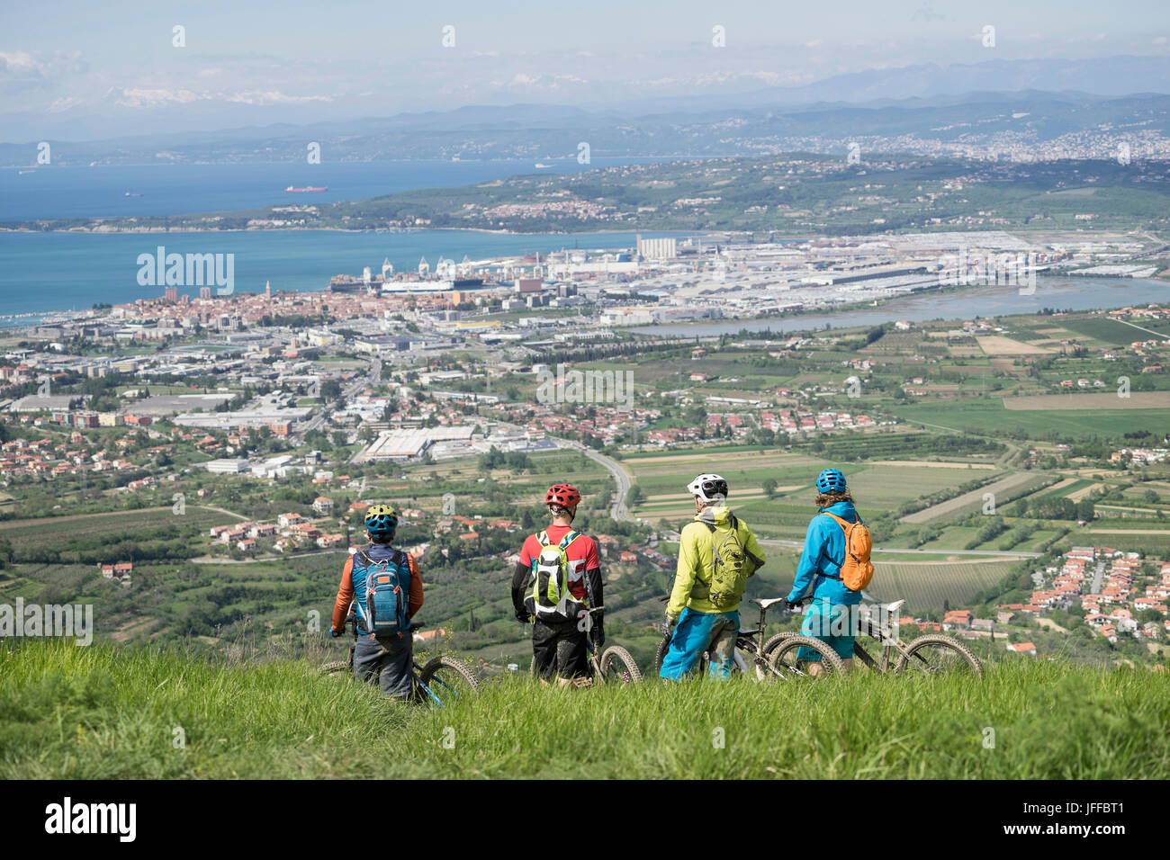 Mountain Biker looking at cityscape and sea from mountain Stock Photo