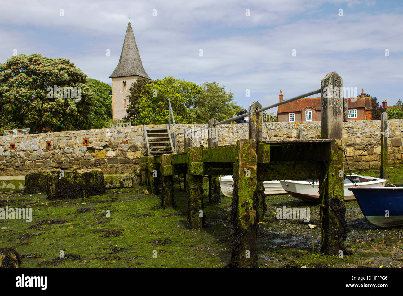 A small wooden jetty covered with barnacles and seaweed in the harbour at Bosham village in West sussex in the South of England Stock Photo
