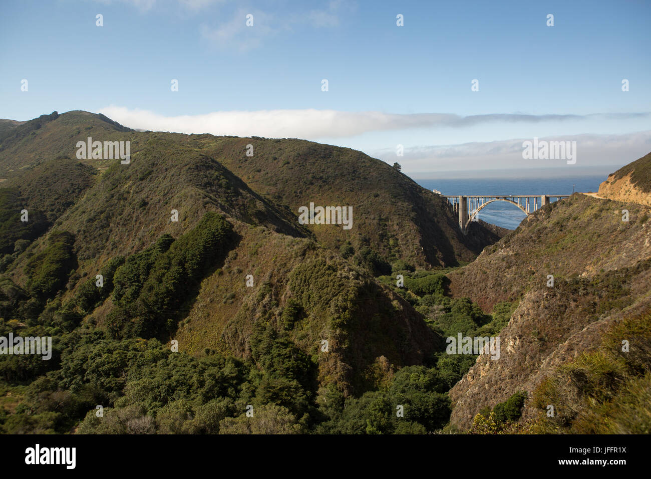A scenic view of the Bixby Creek Bridge, a concrete, open-spandrel arch bridge, on the Pacific Coast Highway, and nearby mountains. Stock Photo