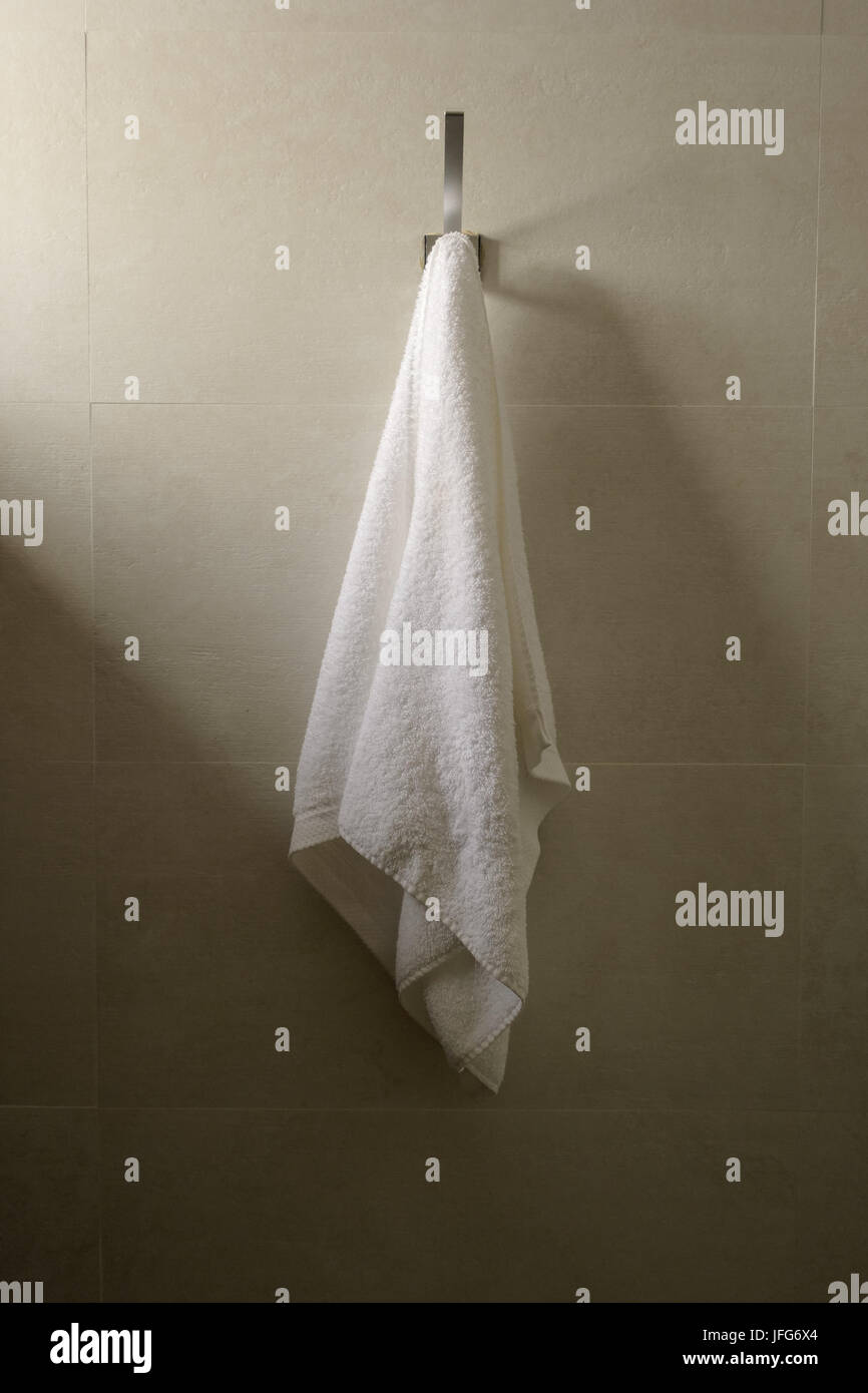 White bath towel hanging on a bathroom wall Stock Photo