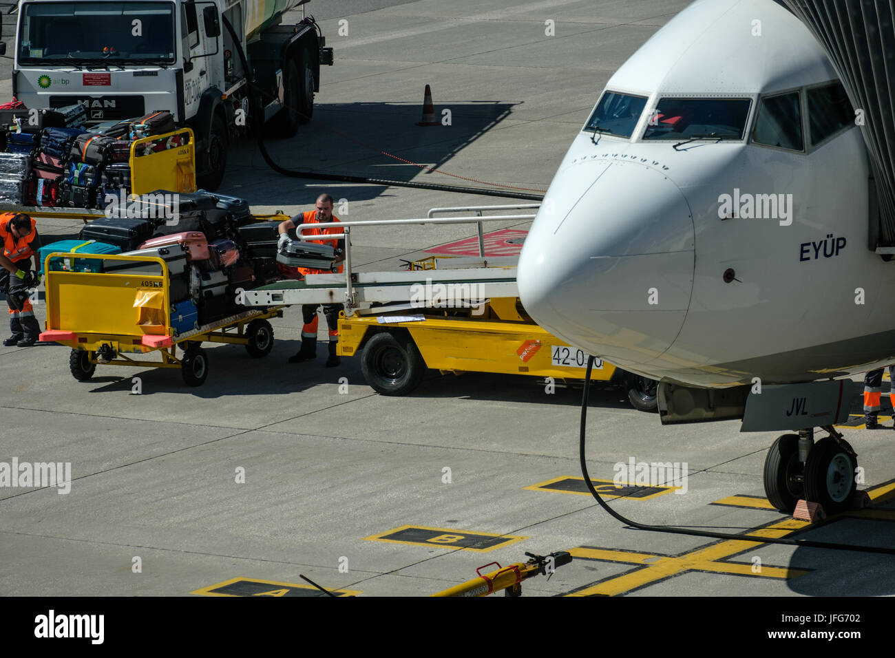 Man loading luggage into airplane at airport tarmac Stock Photo