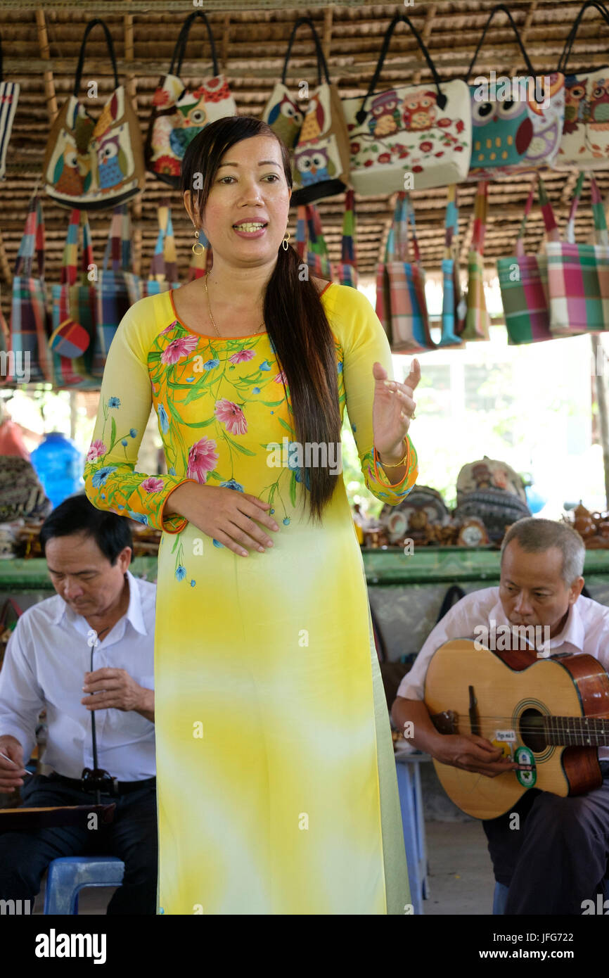 Woman with yellow Ao Dai dress singing traditional vietnamese songs Stock Photo