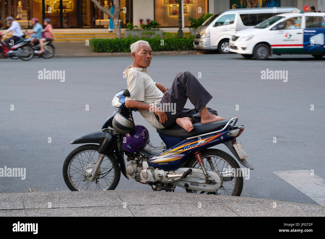 Old vietnamese man resting on this motorcycle Stock Photo