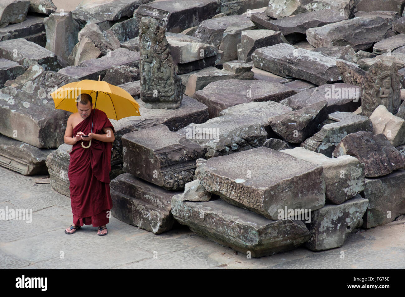 Buddhist monk on holidays using his smartphone while visiting Angkor Wat temple complex in Cambodia, Asia Stock Photo