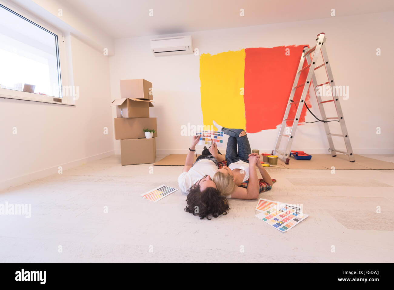 Happy young couple relaxing after painting a room in their new house on ...