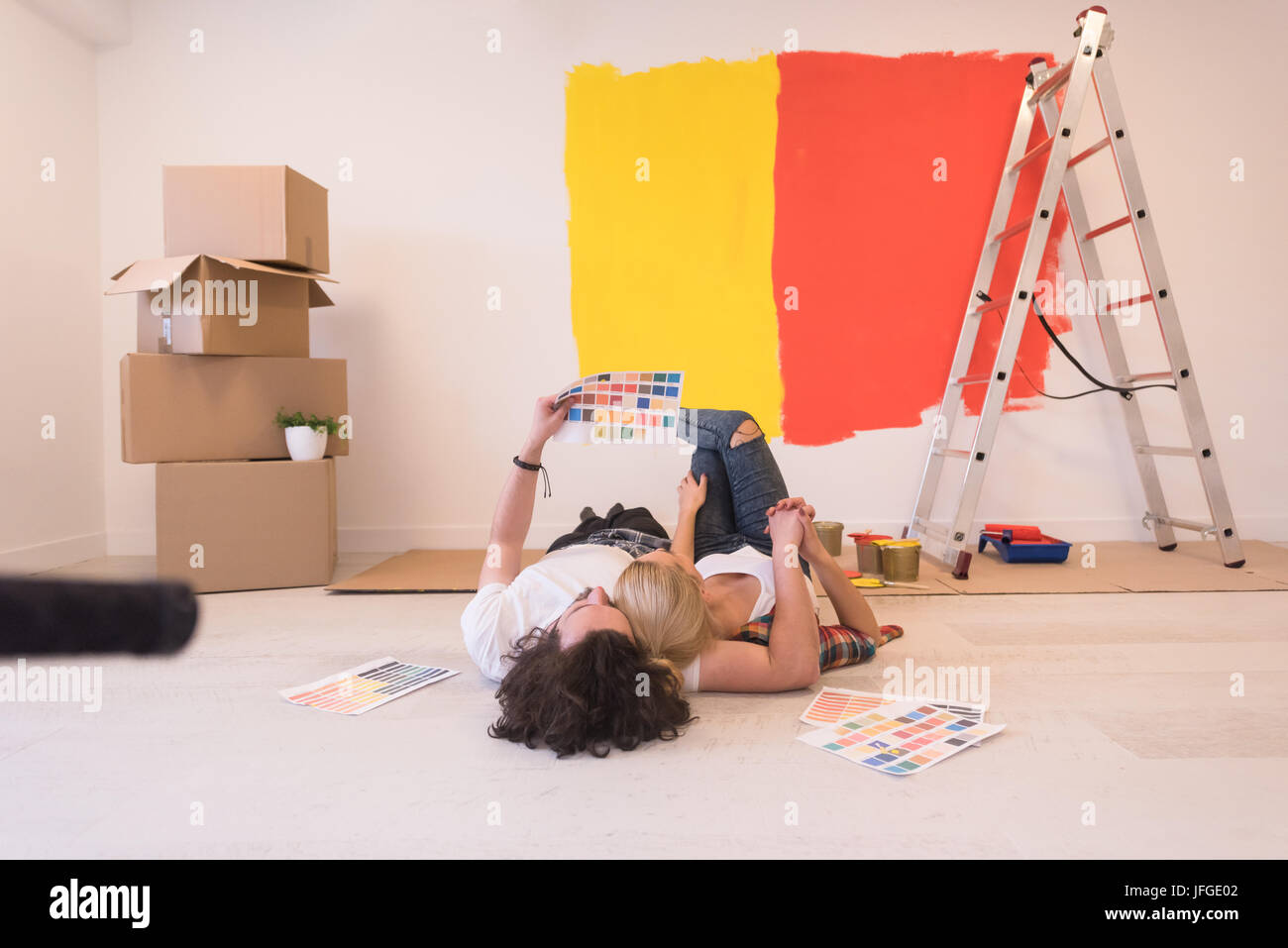 Happy young couple relaxing after painting a room in their new house on ...