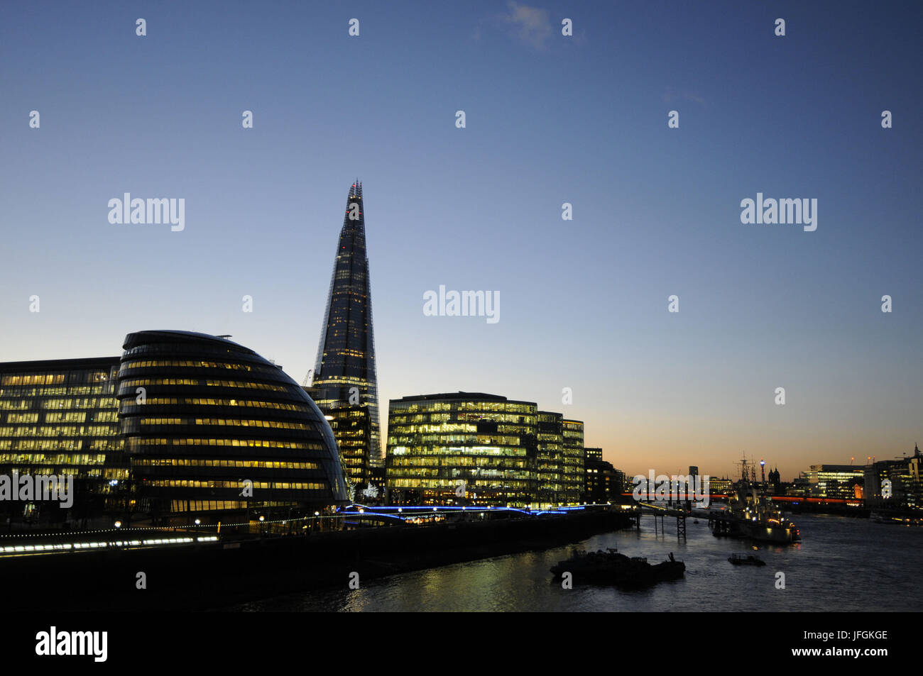 View along River Thames to City Hall and The Shard at Dusk with HMS Belfast moored in the Thames, London, England Stock Photo