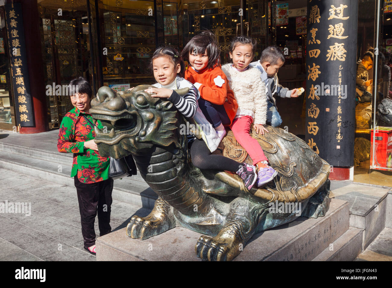China, Shanghai, Yuyuan Garden, Children Playing on Bronze Dragon Headed Turtle Statue Stock Photo