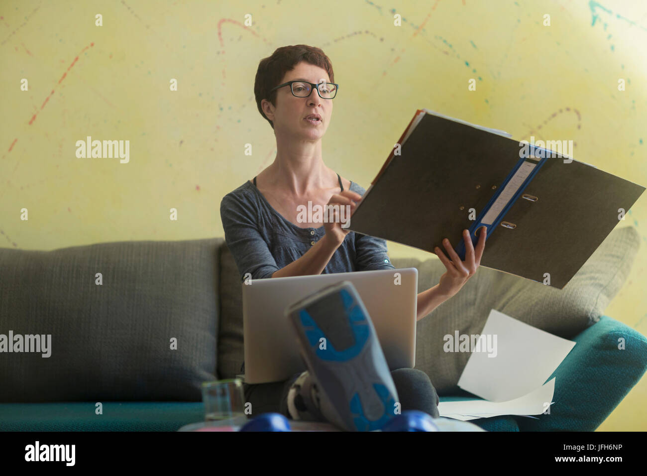 Woman with broken leg working on laptop and reading document Stock Photo