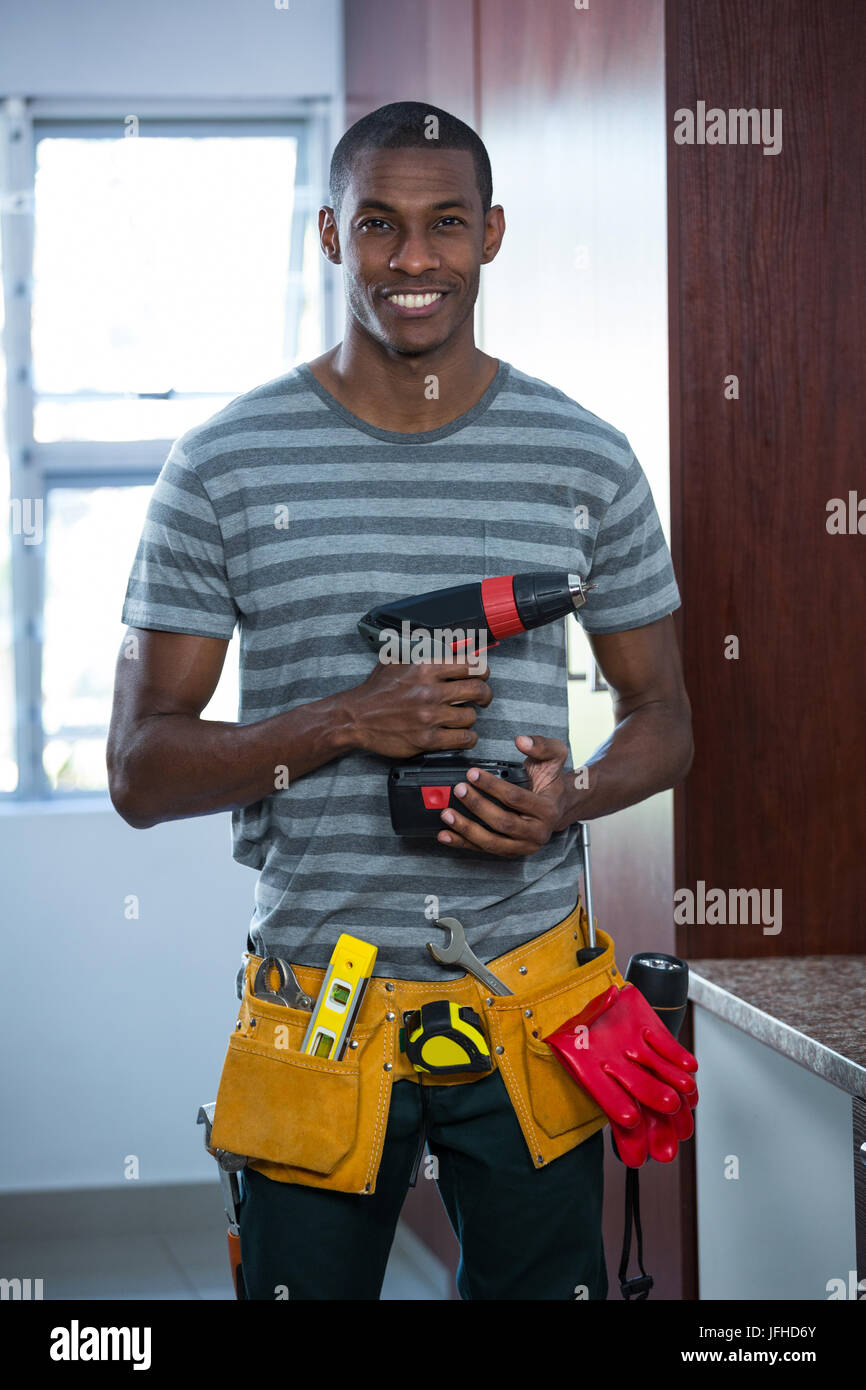 Smiling manual worker holding a drill machine Stock Photo