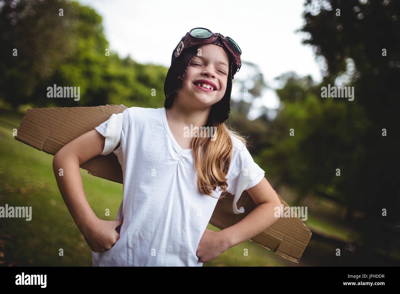 Happy girl standing in the park with hand on hip Stock Photo - Alamy
