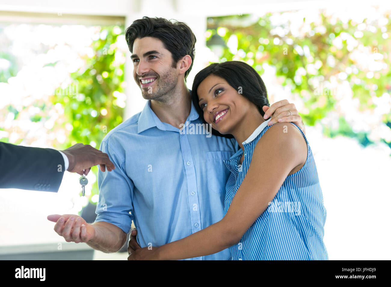 Real estate agent giving house keys to the couple Stock Photo - Alamy