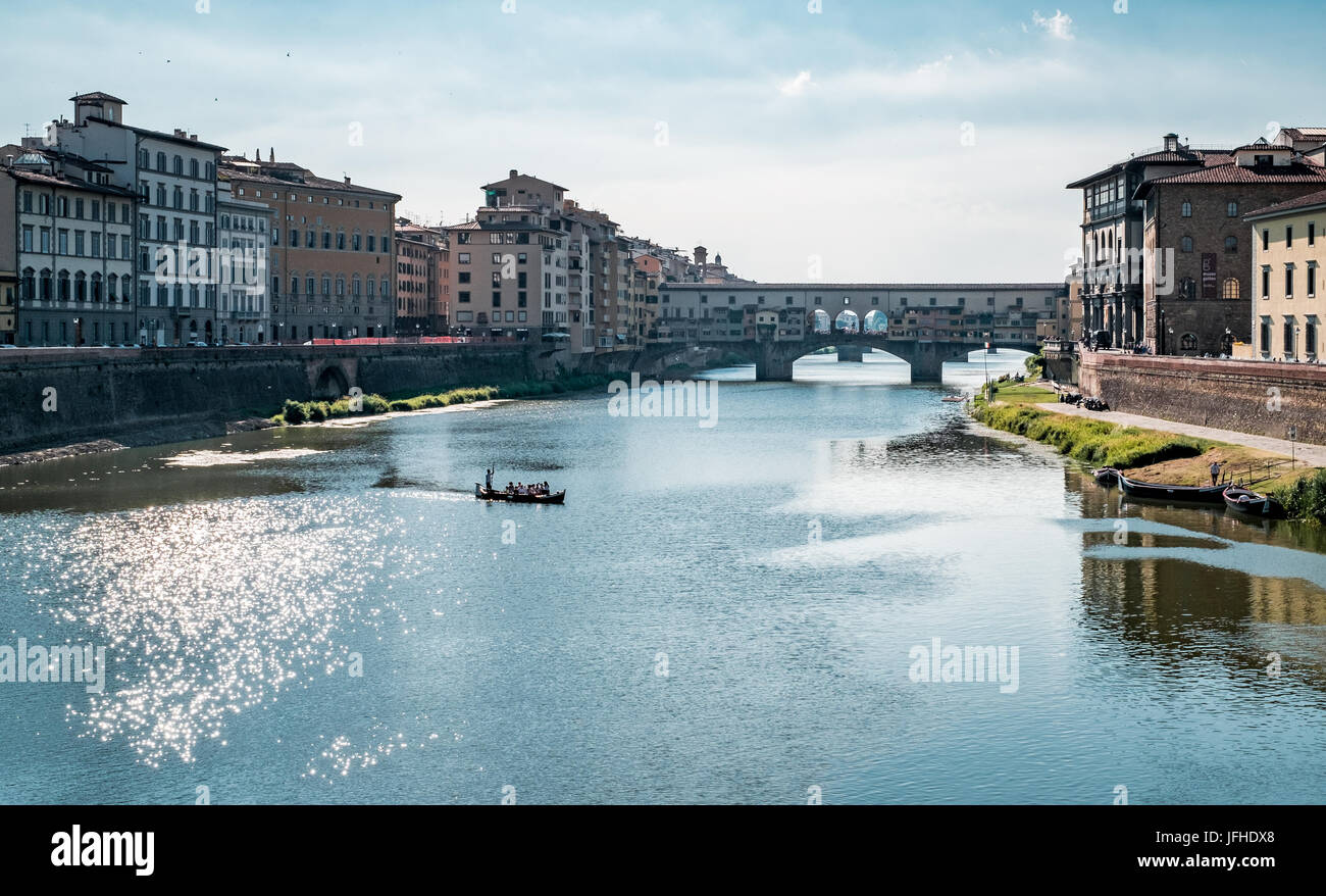 small tourist boat floating on the Arno river  near the Ponte Vecchio in Florence Stock Photo
