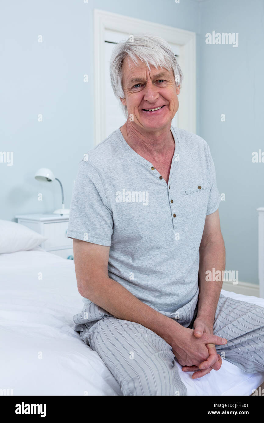Portrait of senior man sitting on bed at home Stock Photo