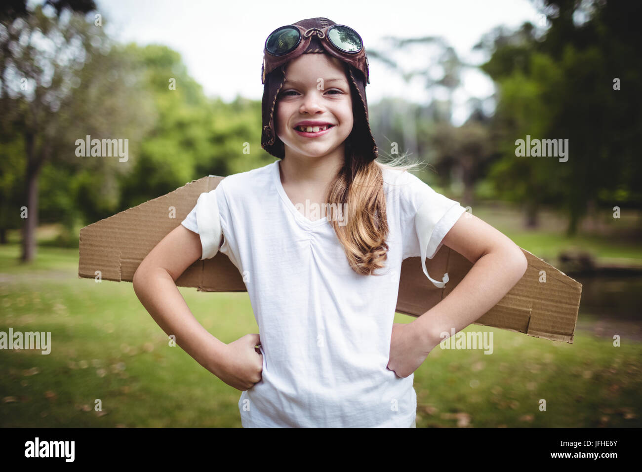 Happy girl standing in the park with hand on hip Stock Photo - Alamy