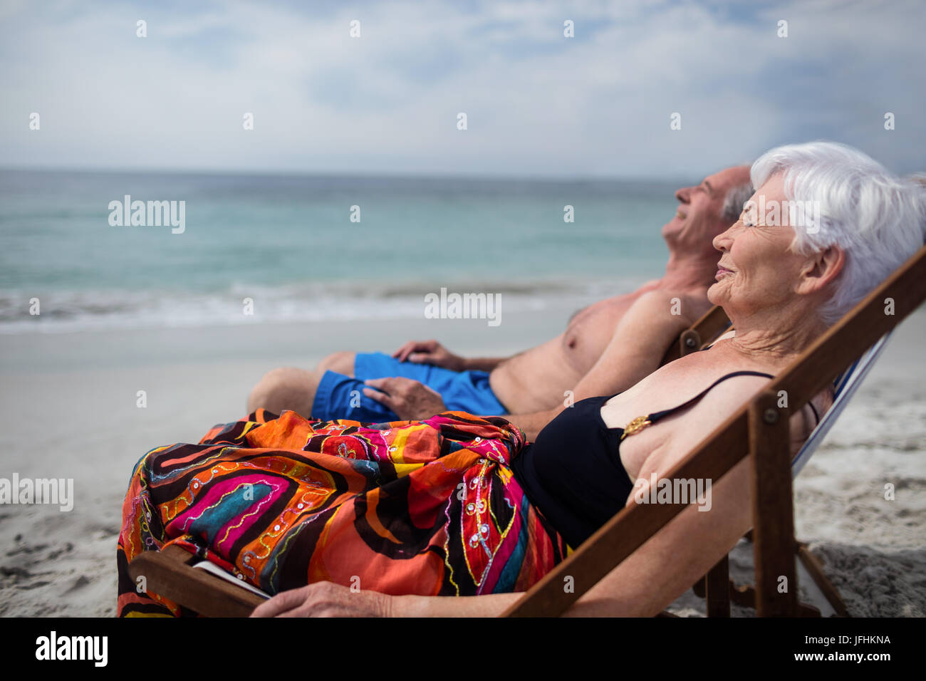 Happy senior couple relaxing on deckchairs at beach Stock Photo - Alamy