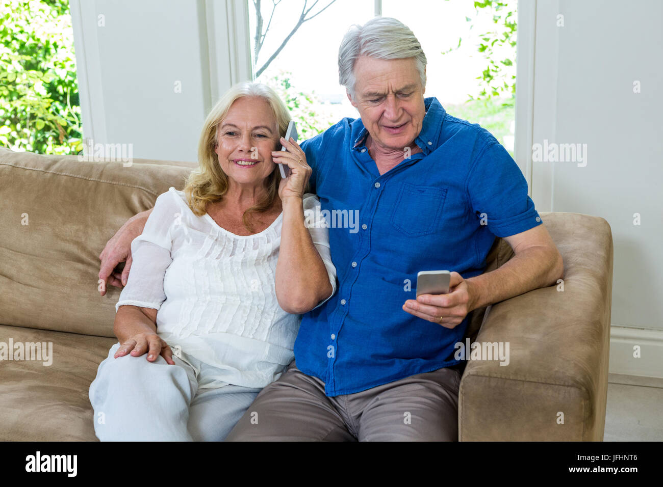 Senior couple using mobile phones while sitting at home Stock Photo - Alamy