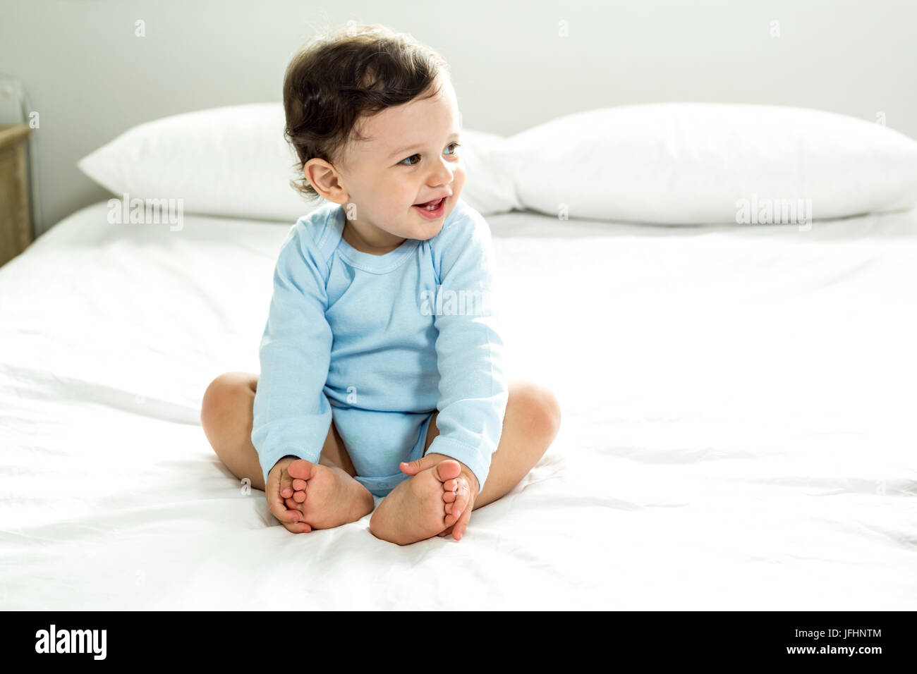 Smiling baby boy sitting on bed hi-res stock photography and images - Alamy