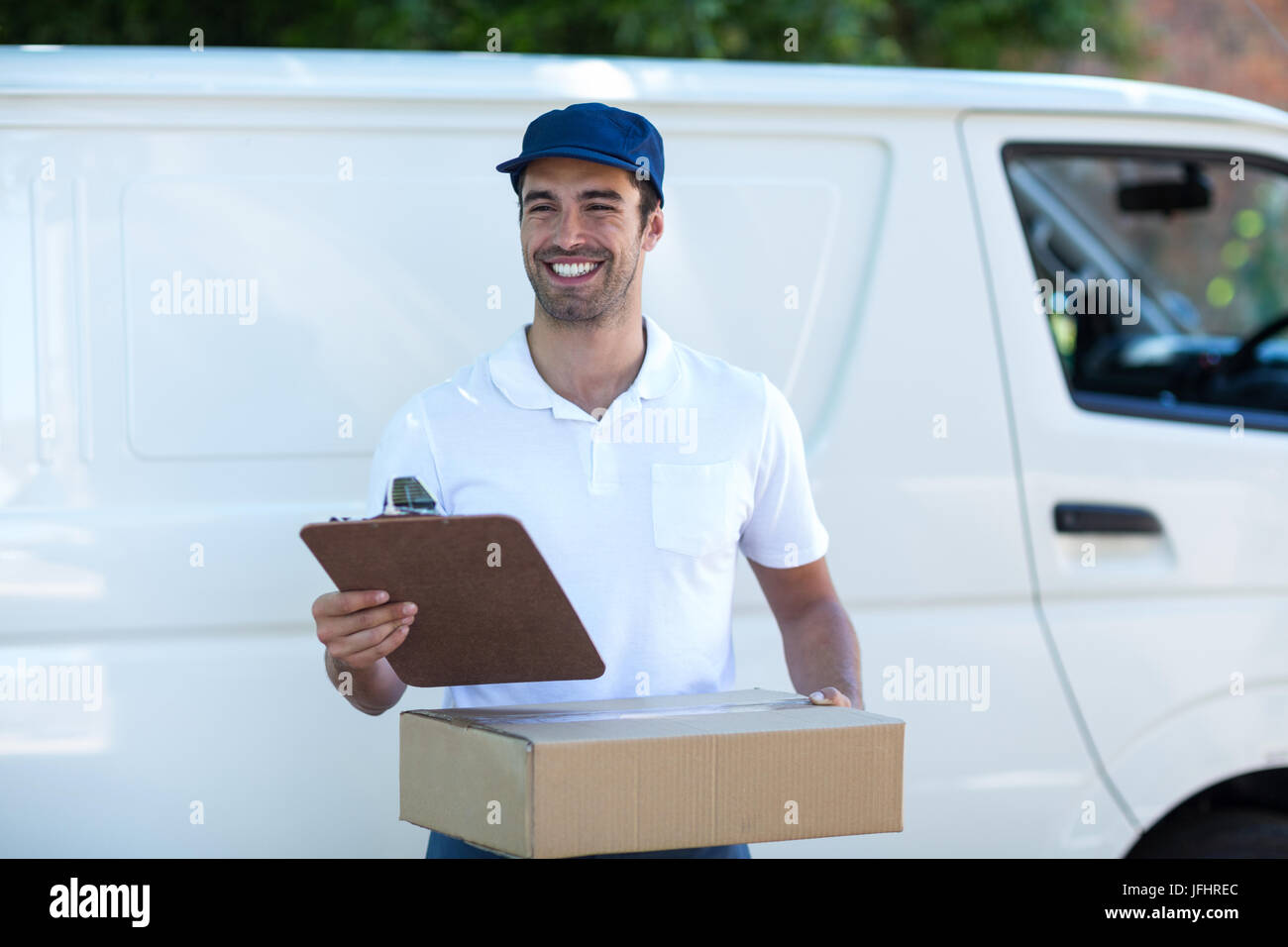 Smiling delivery man with clipboard and cardboard box Stock Photo - Alamy
