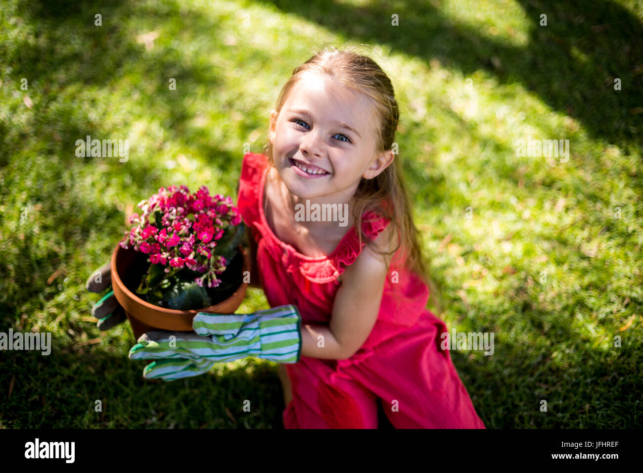Portrait of smiling girl holding flower pot in yard Stock Photo - Alamy