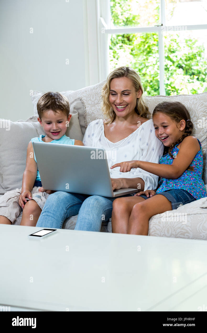 Happy children with mother using laptop on sofa Stock Photo - Alamy