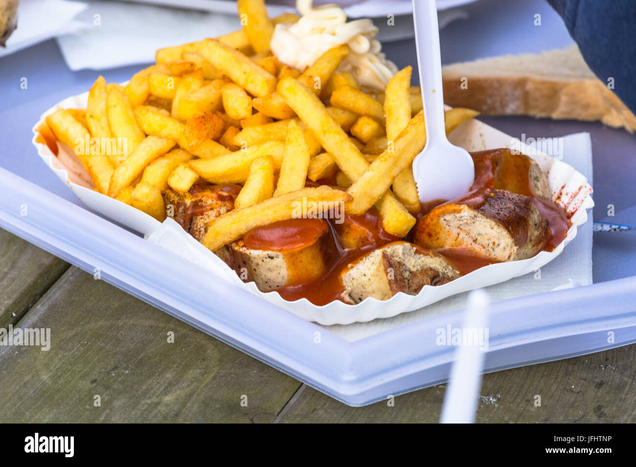 Paper bag with curried sausage and French fries Stock Photo