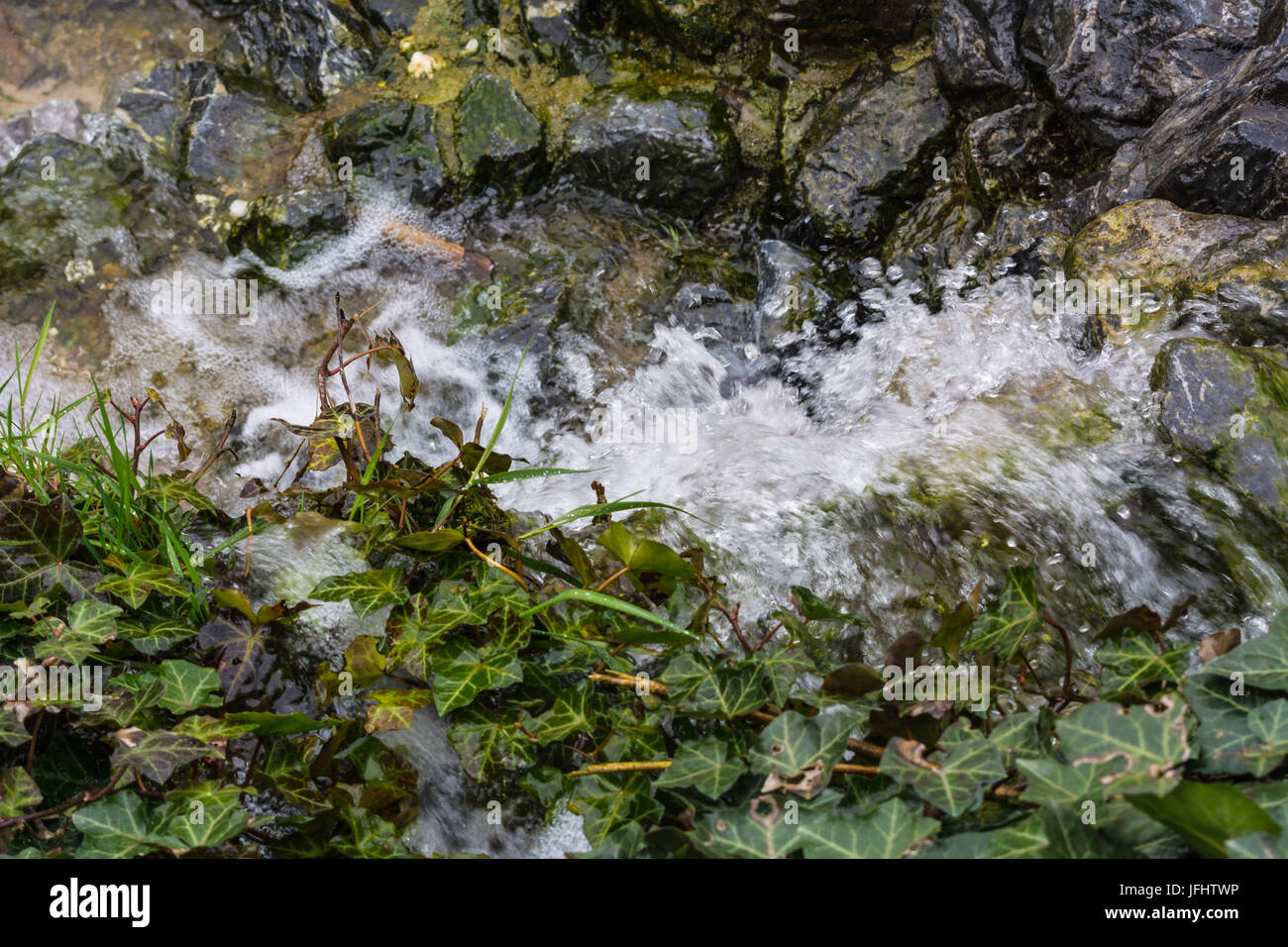 Small waterfall, cascade flowing over mossy boulders Stock Photo