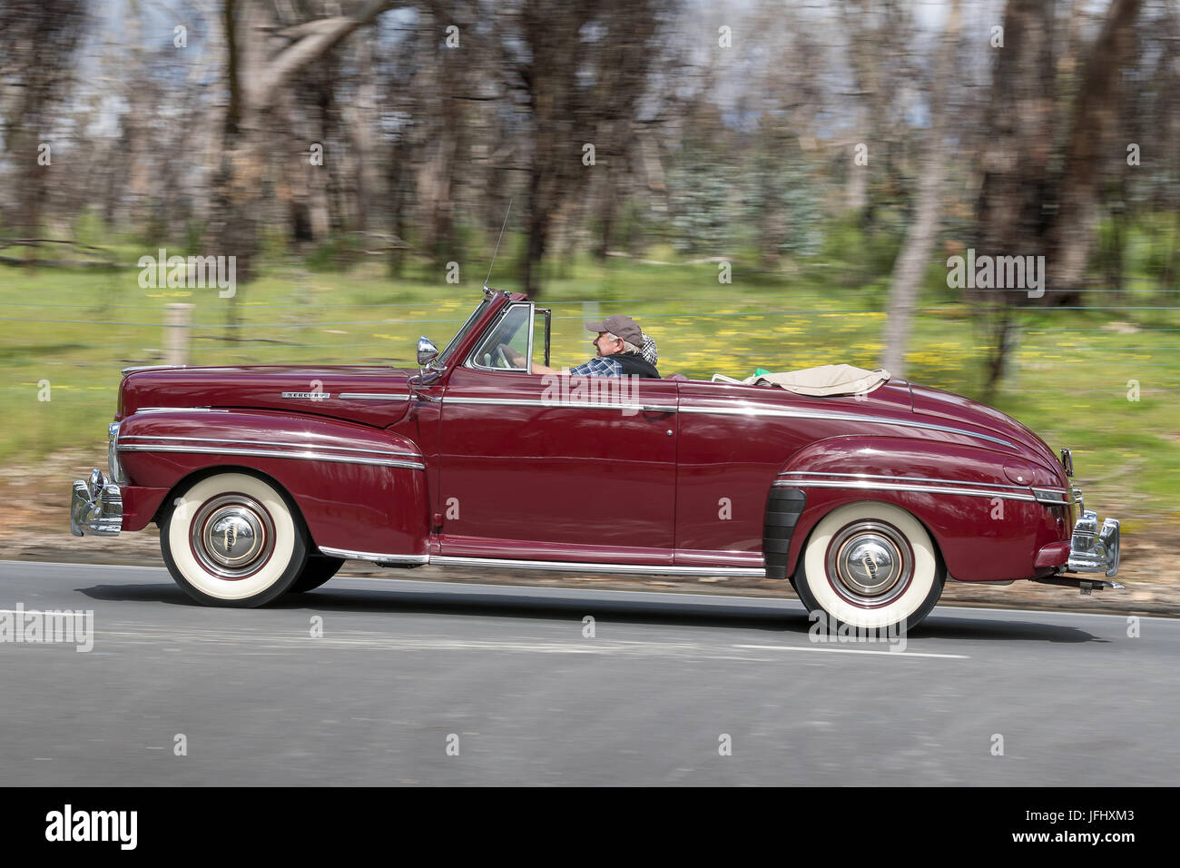 Vintage convertible car driving on country roads near the town of