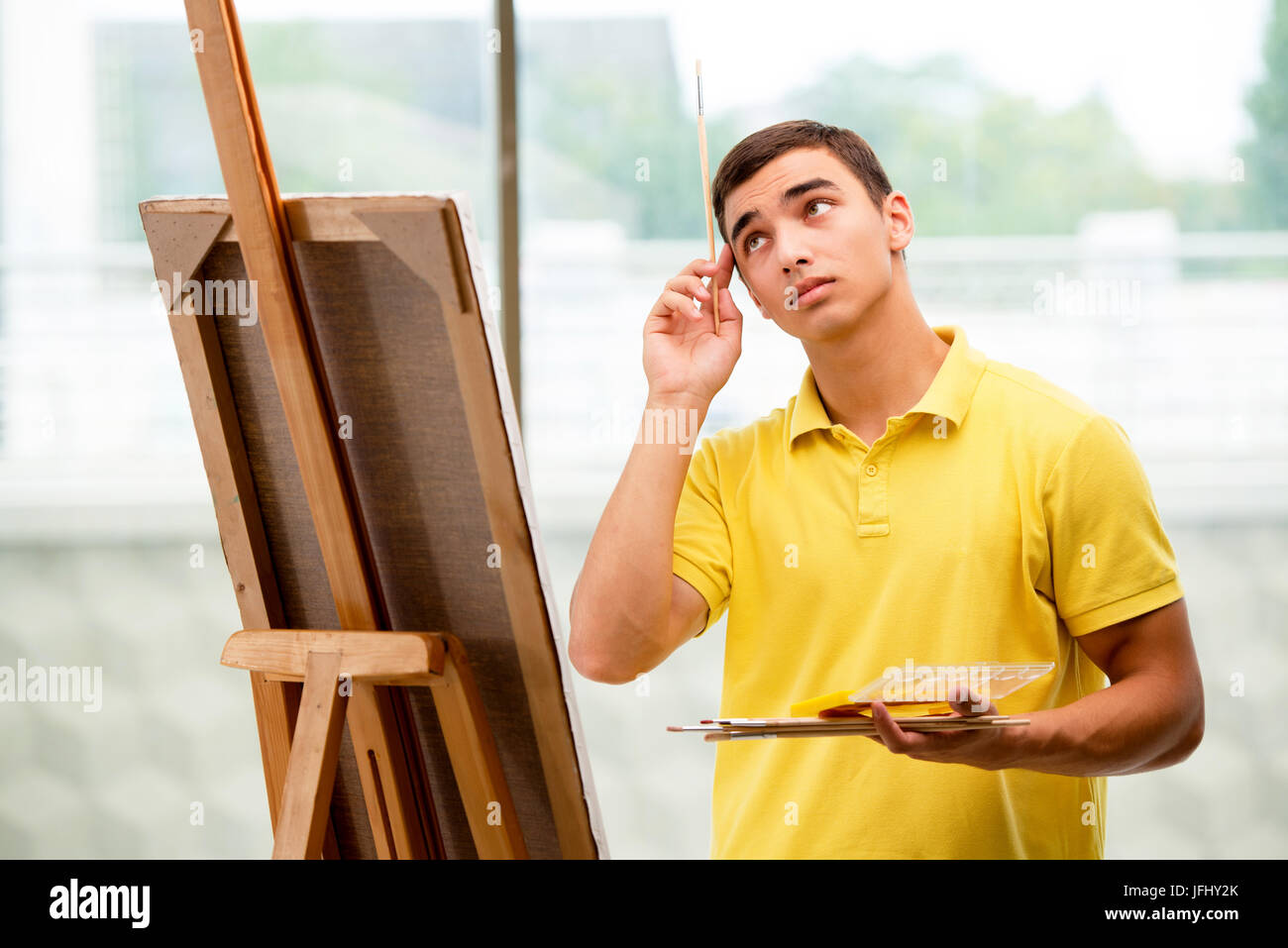 The young male artist drawing pictures in bright studio Stock Photo - Alamy