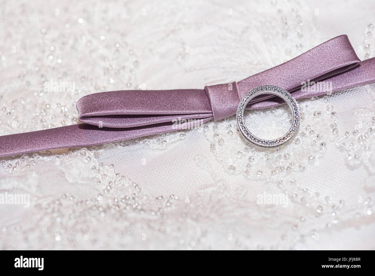 Ring made of platinum with diamonds and mauve ribbon on a background made of lacy Stock Photo